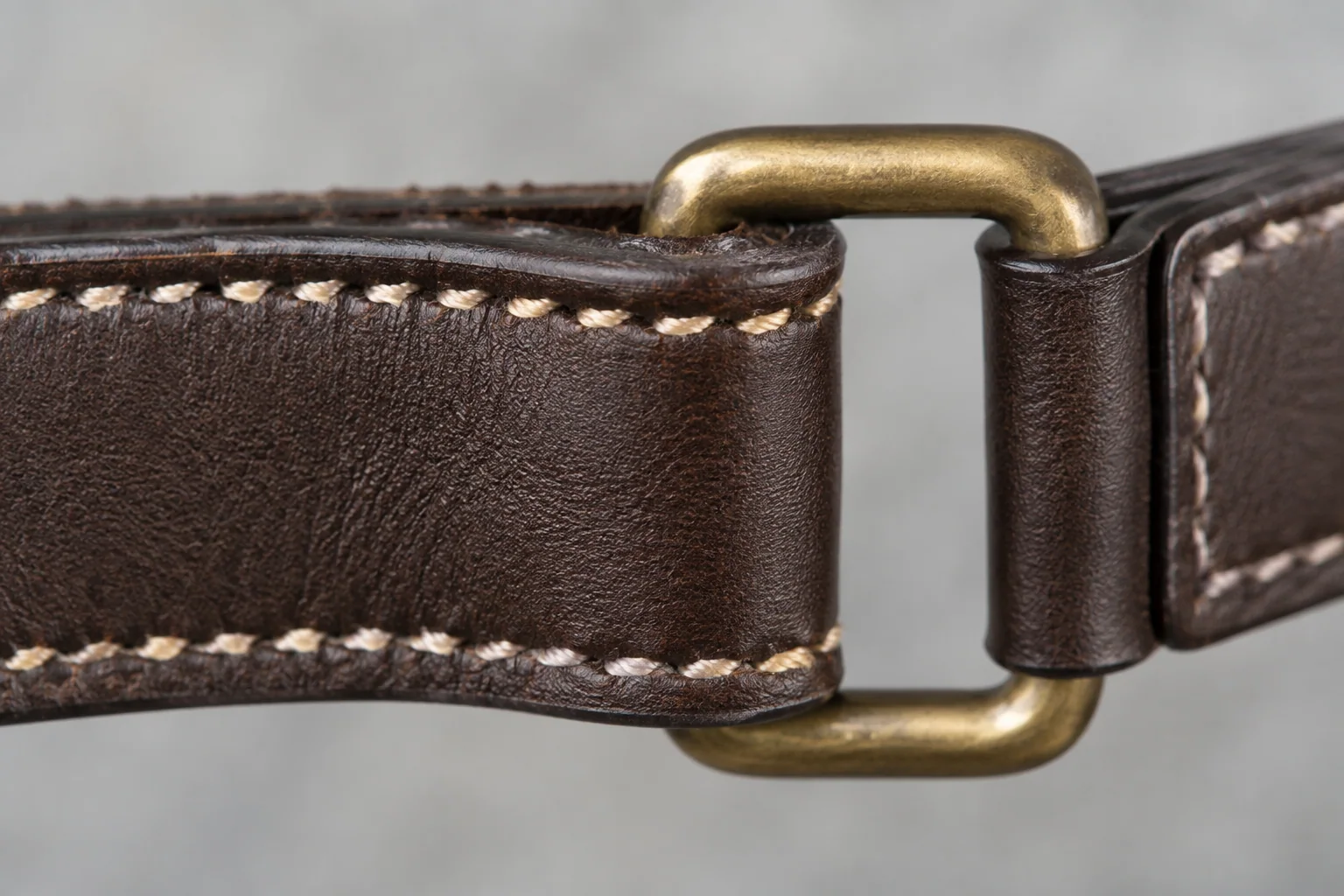 Illustrative close-up of leather strap stitching, finished edges and a brass ring